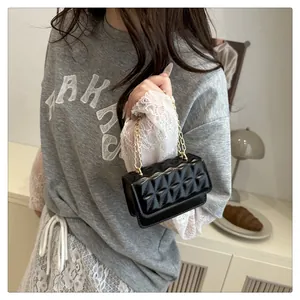 Detalle del mini bolso negro acolchado con cadena dorada y diseño de rombos