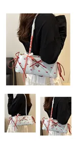 Detail of light blue handbag featuring red bow prints and white lace trim accents