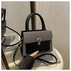 Detail of grey fabric and black leather handbag with a gold horseshoe lock closure