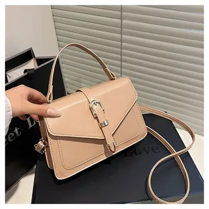 Close-up of minimalist beige square bag with golden buckle and leather handle