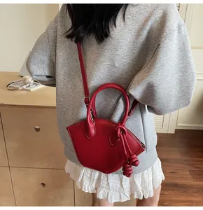 Vue détaillée d'un sac à main asymétrique rouge avec nœud en cuir et bandoulière fine