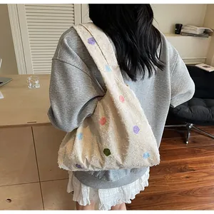 Detailed close-up of large cream-colored polka dot tote bag on female model shoulder