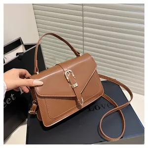 Detail of a brown leather crossbody bag with vintage flap and gold metal buckle