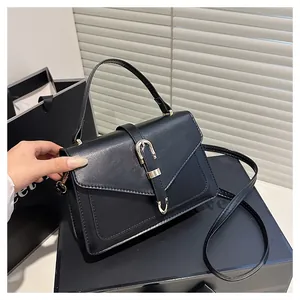 Close-up of black crossbody bag with golden horseshoe buckle and gift box packaging