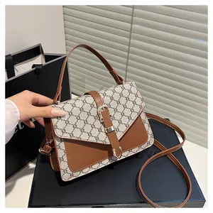 Detailed view of canvas crossbody bag with brown leather trim and metal buckle clasp