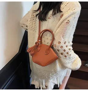 Sac bandoulière demi-lune en cuir caramel avec nœuds porté par un modèle