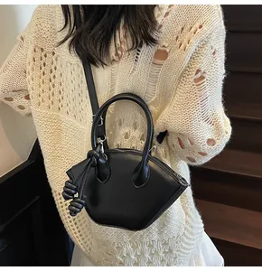 Détail d'un sac bandoulière noir en forme d'éventail avec pompons en cuir sur un mannequin