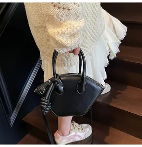 Détail d'un sac à main chic en cuir noir avec poignées nouées et bandoulière amovible