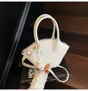 Vue macro d'un sac à main blanc en cuir en forme d'éventail avec nœud et bandoulière