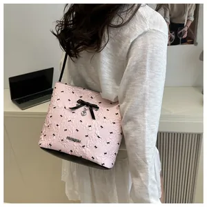 Dettaglio della borsa sottobraccio rosa a pieghe con motivi a fiocco e ciondolo a cuore