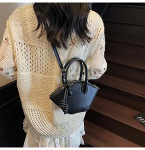 Detail of black shell crossbody bag with side rope tassel and adjustable shoulder strap