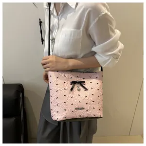 Dettaglio borsa a tracolla rosa con fiocchi neri e ciondolo a cuore su modella