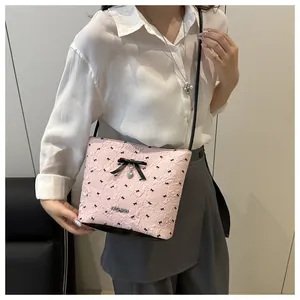 Dettaglio borsa rosa con stampa a fiocchi neri, ciondolo a cuore e logo in metallo