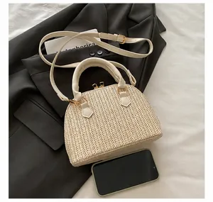 Detalle macro del bolso de paja beige con cremalleras doradas y comparación de tamaño