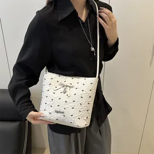 Borsa sottobraccio crema con texture floreale, dettaglio fiocco e ciondolo a cuore