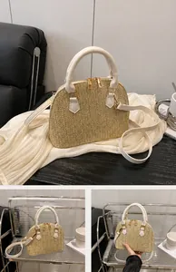 Detalle de bolso de paja caqui con doble cremallera dorada y asas de cuero blancas