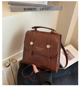 Detail of dark brown vintage PU leather backpack with gold lettering and metal buckles
