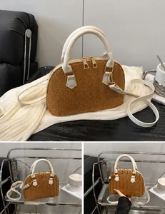 Detalle del bolso de paja marrón con correas de cuero blanco y cierres dorados