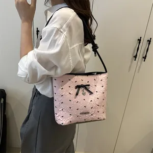 Borsa sottobraccio in jacquard rosa con fiocchi neri e ciondolo a cuore sulla spalla