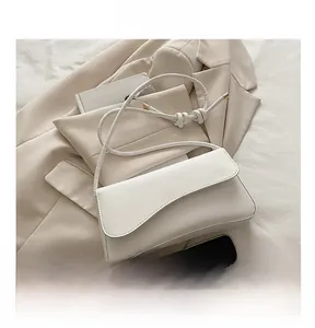 Detail shot of white shoulder bag with asymmetrical flap and knotted rope strap