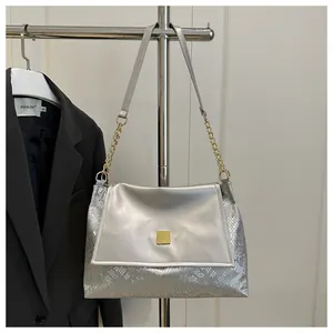 Detail of silver handbag featuring snakeskin texture and golden square metal buckle hardware