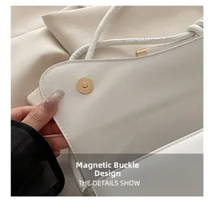 Detailed close-up of gold magnetic closure on cream leather saddle shoulder bag