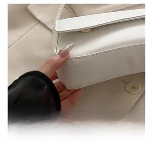 Detailed macro view showing precision stitching and gold hardware on white leather handbag