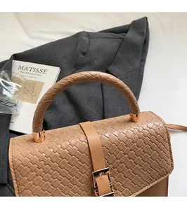 Detail of light brown woven PU leather handbag with round handle and metal buckle