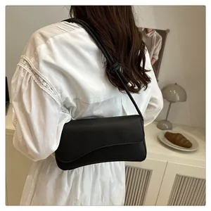 Detail of minimalist black leather underarm bag with decorative knotted shoulder strap