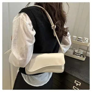 Close-up of cream shoulder bag with stylish wave-shaped flap and knotted strap detail