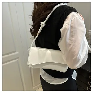 Detail of white minimalist shoulder bag with unique knotted strap on model shoulder
