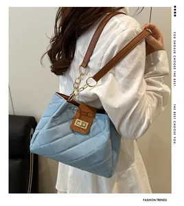 Detalle de bolso acolchado azul claro con correa de cuero marrón y cierre de metal oro