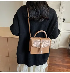 Brown faux leather crossbody bag with snake texture flap shown on a model outfit