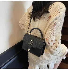 Detail of black crossbody bag with snake pattern texture and heart hardware detail