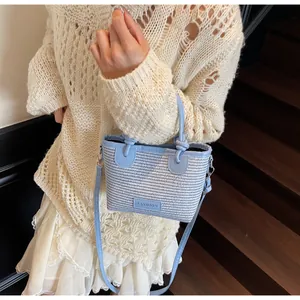 Detail of light blue woven bucket bag with leather handles and fashion label