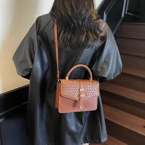 Classic brown crossbody bag with woven handle shown on shoulder in urban setting