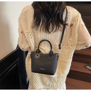 Detail of woven texture on black crossbody bucket bag with knot handle and leather trim