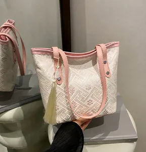 Close-up of the textured jacquard fabric tote bag with elegant pink leather handle and tassel