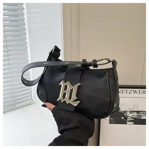 Detalle del bolso baguette de cuero PU negro con gran logo gótico plateado y correa de ojales