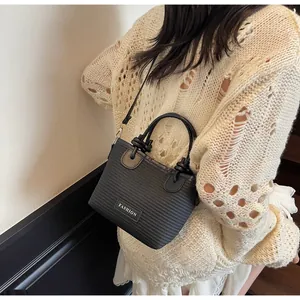 Detail view of black textured bucket bag with FASHION patch and detachable strap