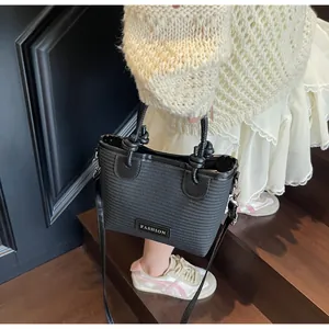 Detail of black woven bucket bag with fashion plaque and knotted handle design