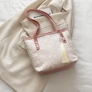 Detailed view of pink geometric jacquard tote bag with stylish leather handles and tassel