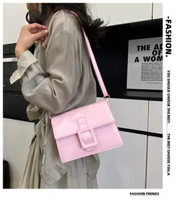 Close-up of pink faux leather crossbody bag with a large decorative buckle flap