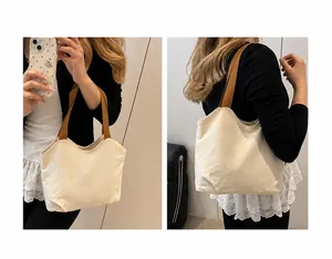 Minimalist canvas tote bag with brown straps shown in handheld and shoulder carry styles