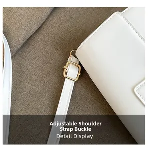 Close-up of adjustable strap buckle on a white leather shoulder bag with gold metal hardware