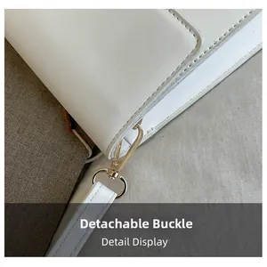 Detail view of the white leather bag featuring a gold-toned detachable metal swivel hook