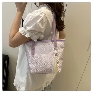 Detail of light purple tote bag with geometric embroidery and yellow tassel charm
