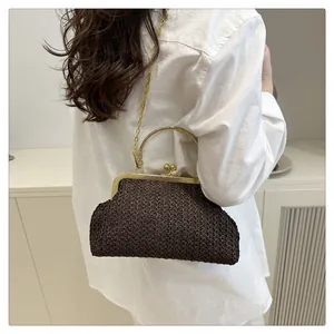 Detail of a dark brown woven shell bag with gold handle and chain on a model