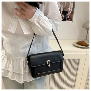 Détail d'un sac à main noir élégant avec boucle dorée en fer à cheval sur un mannequin