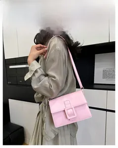 Detail of pink faux leather crossbody bag with large buckle and adjustable strap